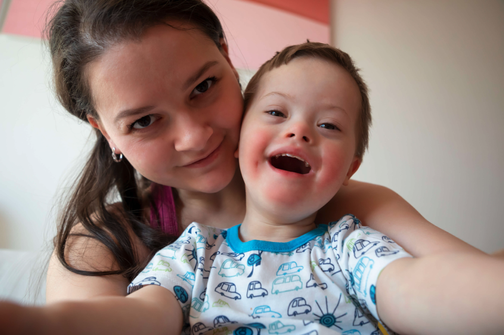 A close-up selfie of a woman and a young boy with Down syndrome, both smiling joyfully, which reflects the hope and support provided by an ABLE account for individuals with special needs.