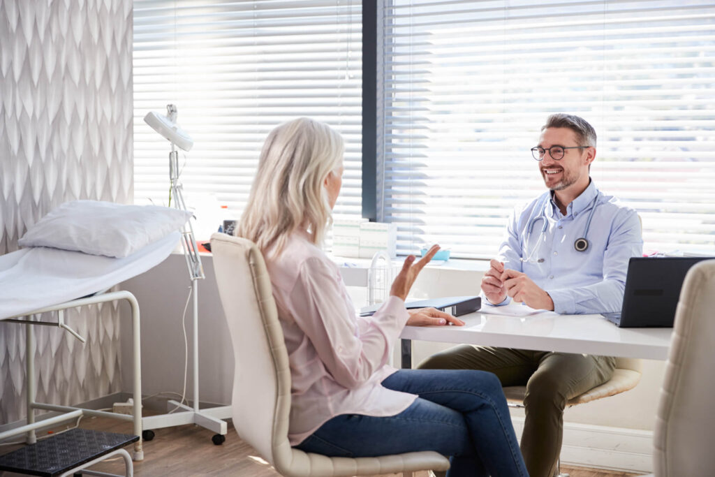 A patient and doctor engage in a friendly conversation in a medical office, an example of the collaborative decision-making supported by a health care proxy.