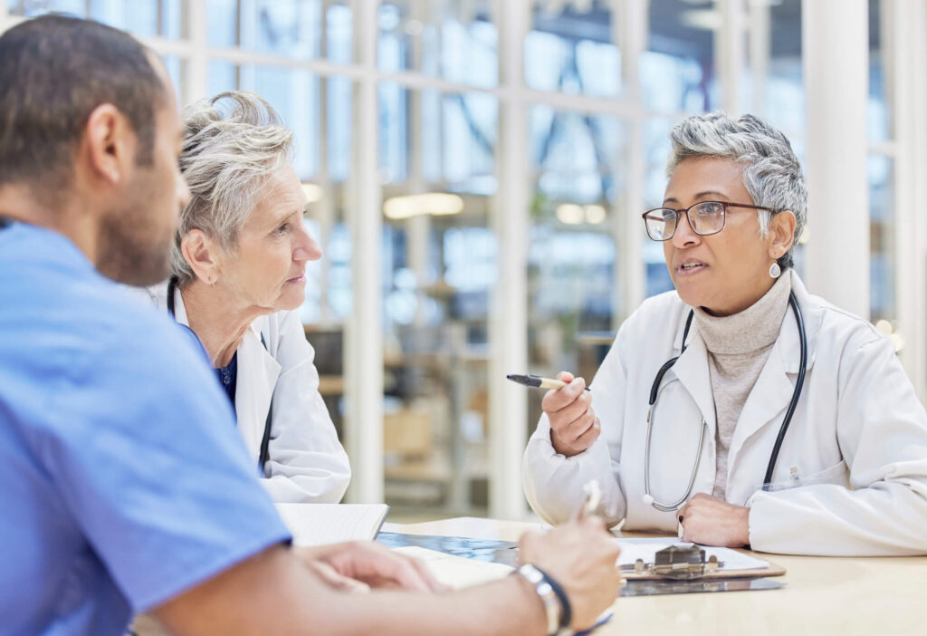 A group of healthcare professionals in discussion, possibly about the roles and responsibilities associated with a health care proxy, in a bright, modern medical facility.