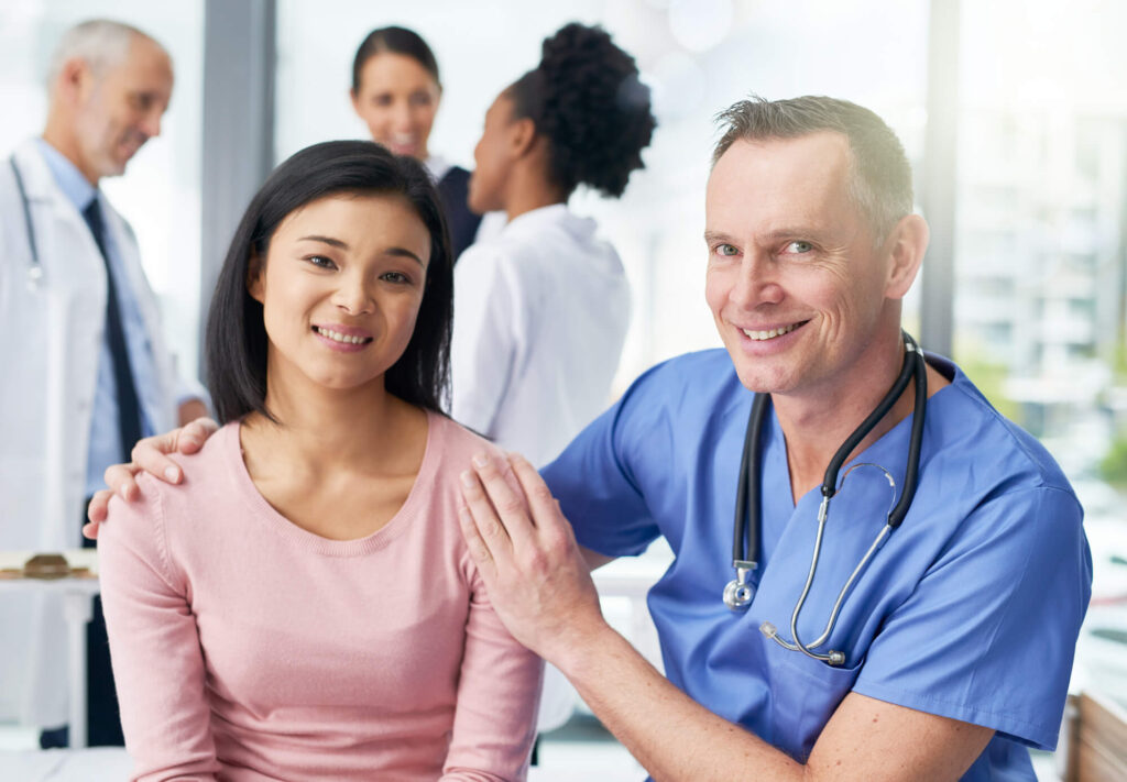 A smiling female patient and a male doctor in scrubs, with a comforting hand on her shoulder, represent the trust and understanding important in a health care proxy relationship.