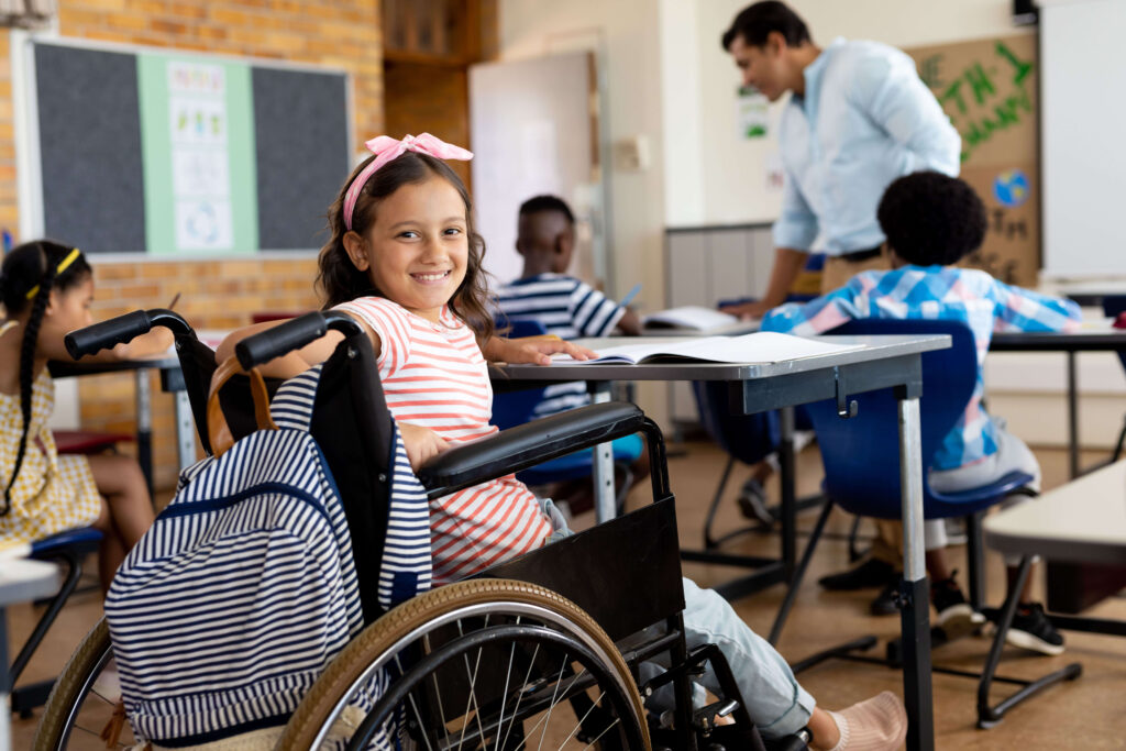 A young girl with a radiant smile in a wheelchair participates in class, illustrating the inclusive education supported by the power of attorney for education.