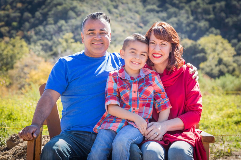 A smiling family of three, with a young boy with Down syndrome, sits outdoors, embodying the proactive care and planning that comes with a power of attorney.