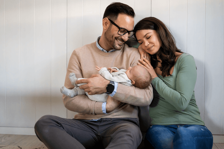 A content couple sits together lovingly cradling their sleeping baby, reflecting the protective nature of special needs trusts.