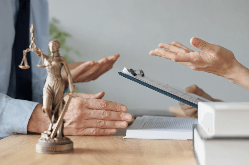 Two individuals in a professional setting discuss documents, with the iconic scales of justice statue in the foreground, symbolizing the legal discussions surrounding a power of attorney.